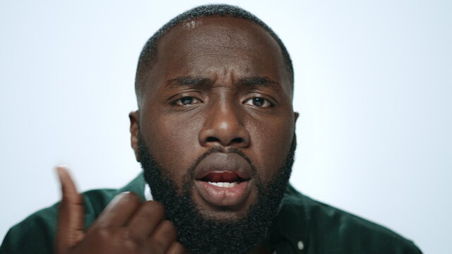 Portrait Of Handsome African American Man Checking Beard In Light Background.