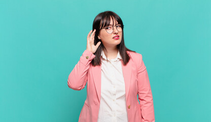 young business woman looking serious and curious, listening, trying to hear a secret conversation...