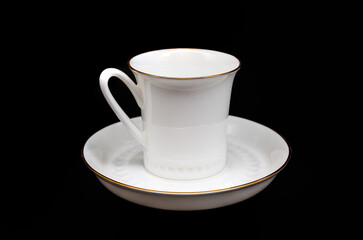 white cup and saucer for coffee on a black background close up