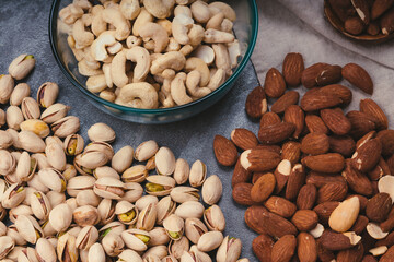 mixed nuts in ceramic bowls, wooden spoon. Almonds, walnuts, cashew nuts, pistachio nuts