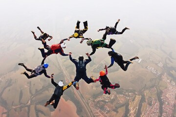 Skydivers holding hands making a fomation. High angle view. - obrazy, fototapety, plakaty