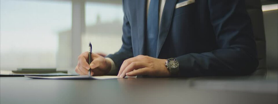 Close-up on the hands of a businessmansigning a contract in a modern workplace.