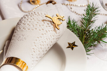 Christmas table setting. White napkin with gold ring.