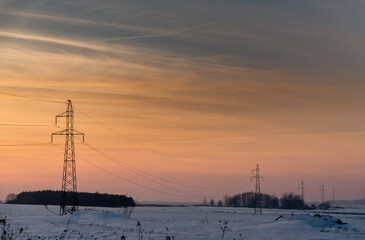 Hi-voltage electric power lines in a wintry foggy landscape.