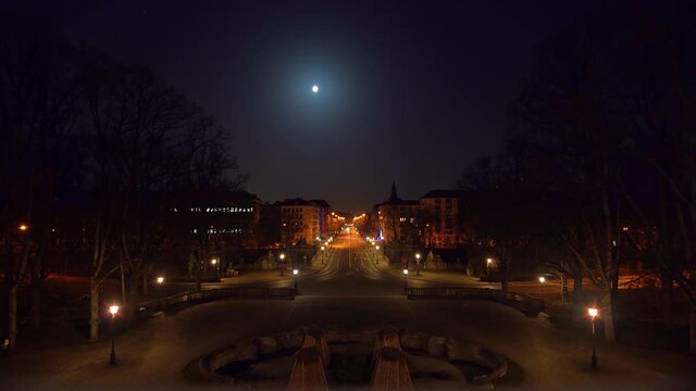 Timelapse of driving cars at night in Munich, the bavarian capital, filmed from a high point of view. Cars are stopping at red traffic lights, driving at green lights under the light of the full moon.