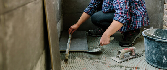 Female bricklayer checking the floor with a level to install a tile floor