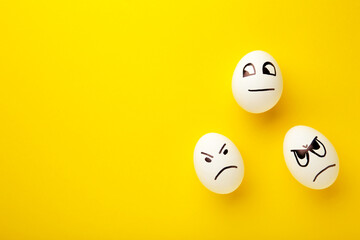 Funny Easter eggs with different emotions on his face on yellow background. Easter composition with copy space.