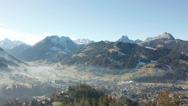 Aerial past trees overlooking beautiful town in valley