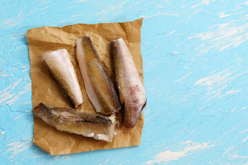 Raw frozen hake fish on a blue background. top view copy space