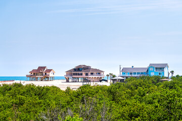 Fototapeta na wymiar Colorful stilted vacation houses on stilts at oceanfront waterfront of Atlantic ocean beach by mangrove forest in summer at Palm Coast, Florida
