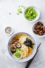 Vegan shiitake mushroom ramen noodles bowl on a grey concrete background, table top view of asian food