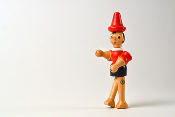 Wooden puppet depicting Pinocchio walking on a white background