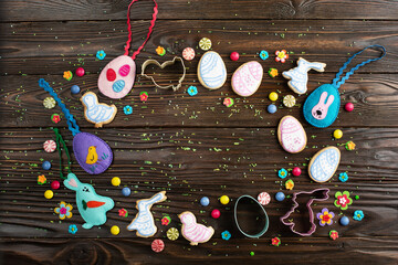 Sugar sprinkles, candies, cookie cutters, sewed felt toys and cookies in shape of egg chicken and rabbit on wooden table background. Flat lay mockup with copy space.