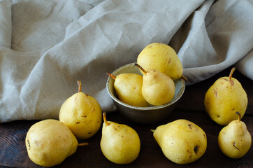 Organic pears in bowl on wooden background. Linen.