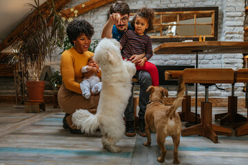 Multiracial family of four having fun with their pets at home