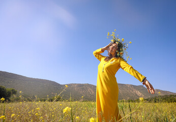 Woman in field with wreath of flowers on her head.