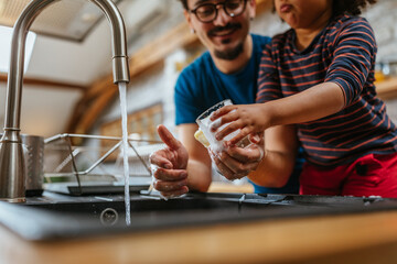 Multiracial father and daughter washing dishes together