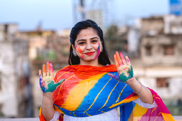 Portrait of happy Indian woman celebrating Holi with powder colours or gulal. Concept of Indian festival Holi.