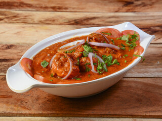 Chicken masala made of indian spices served in a bowl over a wooden rustic background. selective focus