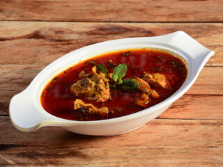Chicken masala made of indian spices served in a bowl over a wooden rustic background. selective focus