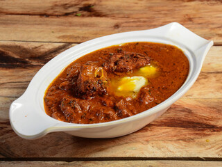 Indian Butter Chicken or Murgh Makhani in a bowl over a wooden rustic background. selective focus
