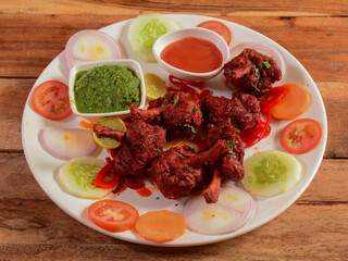 Chicken lollipop is Indian Chinese appetizer served over a wooden rustic background. selective focus