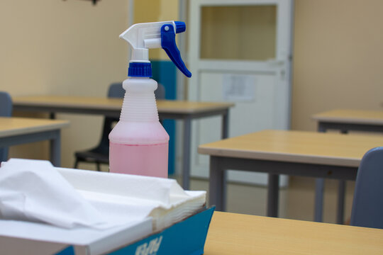 A Spray Bottle And Paper Towels On An Office Or School Desk For Cleaning And Sanitization Concepts For COVID-19 (coronavirus) Concepts.