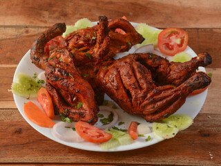Tandoori chicken - prepared by roasting chicken marinated in yoghurt and spices in a tandoor, served over a wooden rustic background. selective focus