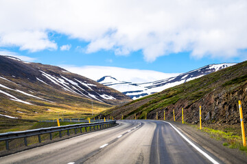 View of snow capped Sulur mountains west of Akureyri with blue sky during sunny summer day and ring...