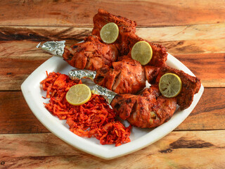 Tandoori chicken - prepared by roasting chicken marinated in yoghurt and spices in a tandoor, served over a wooden rustic background. selective focus