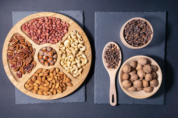 Obraz na płótnie Canvas Mixed nuts on a dark background. Healthy food and snacks. Pecans, Cashews, almonds, peanuts, pine nuts, walnuts hazelnuts