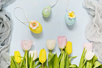 Bouquet of tulips with easter eggs on a light blue background. Happy Easter, spring flowers.