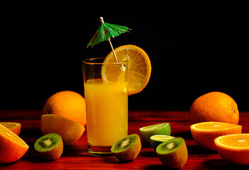 orange juice in a glass cup, kiwi and orange on a wooden table