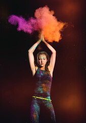 young woman with exploding dry colorful holi powder. holi powder