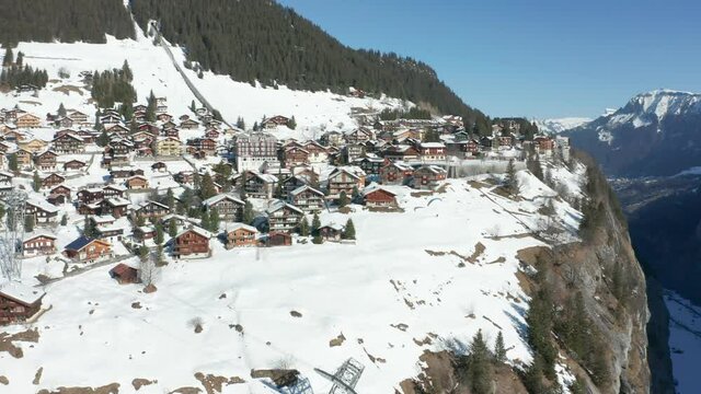 Paraglider jumping of edge of mountain near beautiful Swiss town