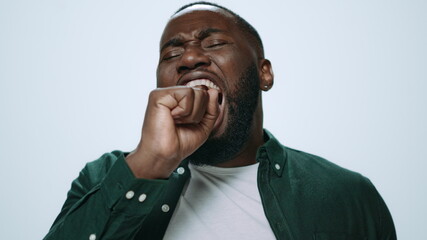 Portrait of tired african handsome man posing on grey background in studio.