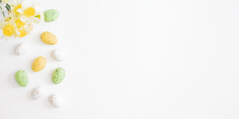 Flat lay easter composition with daffodils in a vase and eggs on white background