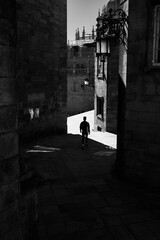 A young man walks down a shady street between stone buildings