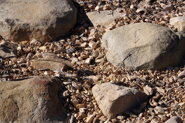 High angle full frame close-up view of a dry desert ground with rocks and stones and gravel