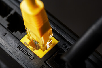 A yellow patch cord is inserted into the Wi-Fi port of the router to access the Internet.