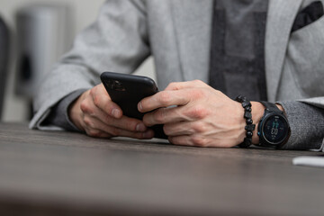 partial view of businessman with hands in lock sitting at table, business concept, wristwatch
