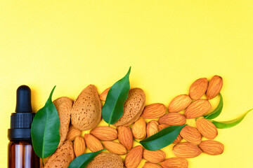 Almond oil and almonds on a yellow background. Organic Almond Oil.