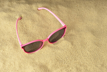 Pink glasses on the sand close up. Glasses on the beach. Summer, sea and vacation concept.