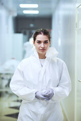 Portrait of young nurse in protective wear looking at camera standing in the corridor at hospital