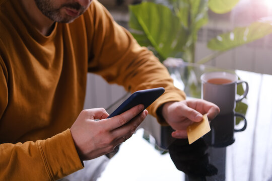 Man in yellow pajamas sitting at the table with credit card and phone shopping online