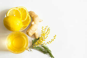 Fototapeta na wymiar Herbal tea in a cup, ginger, lemon and acacia - strengthen immune system in the cold season. Allergies, fever, flu. Vitamin drink for health and ingredients on a white background. Copy space, flatly