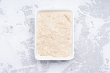 white sauce in white bowl on gray cement background