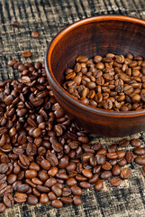 Coffee beans close up. Coffee in a clay bowl on a wooden board. Coffee texture on a black shabby table.