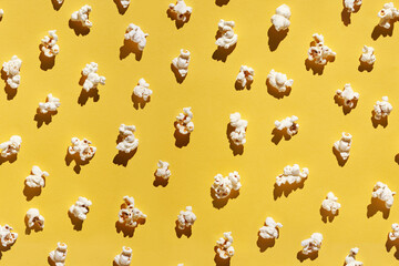 White popcorn design. Creative wallpaper. Yellow bright background. Cinema food concept. Film delicious snack. Many different pieces. Trendy pattern. Top view layout. Flatlay.