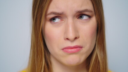 Naklejka premium Closeup worried woman looking at camera on grey background in studio. 